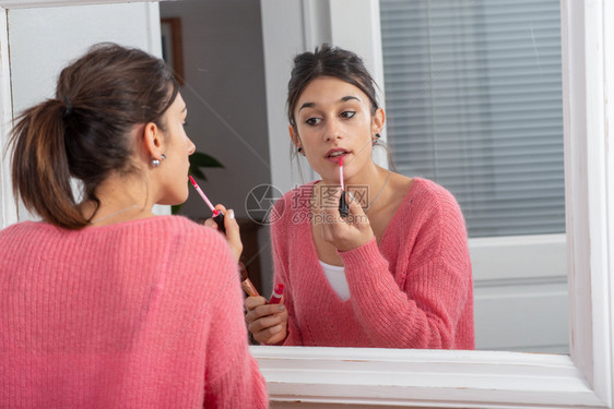 一个年轻的黑发女人在镜子里化妆图片