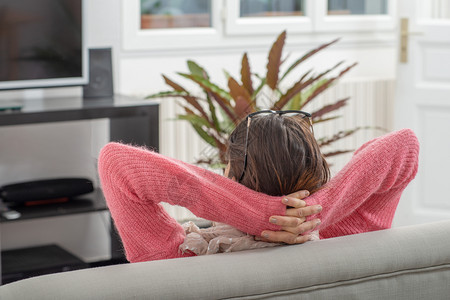 一个年轻黑发女人穿着粉红色毛衣睡在沙发上图片