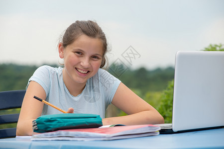 一个十几岁的女孩在花园里做功课图片