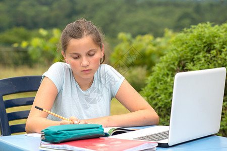 年轻少女在花园做家庭作业图片