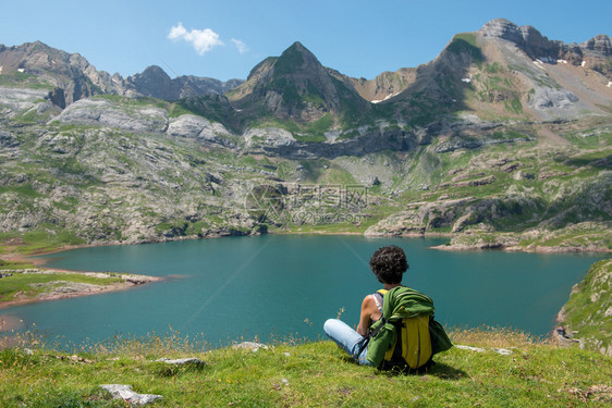 在比利牛斯山的湖边一位女徒步旅行者休息看着湖图片