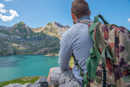 一个男人徒步旅行者休息和看着湖在比利牛斯山图片