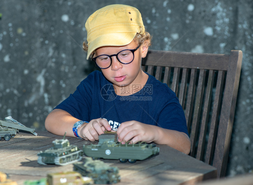 一个小男孩黄色帽子和玩具外面的图片