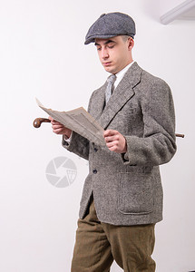 穿着戴帽子阅读1940年风格报纸的旧衣服青年男子背景图片