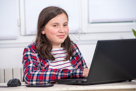 年轻少女用笔记本电脑做家庭作业图片