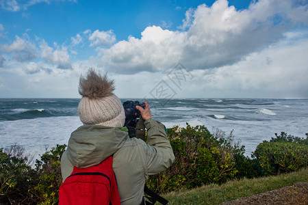 在法国比亚里兹暴风雨中工作的女摄影师图片
