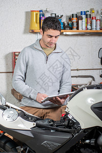 一个年轻人使用摩托车旁边的平板电脑图片
