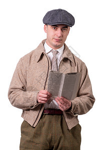 一名穿着戴帽子的古董服装年轻人阅读1940年风格的报纸白色图片
