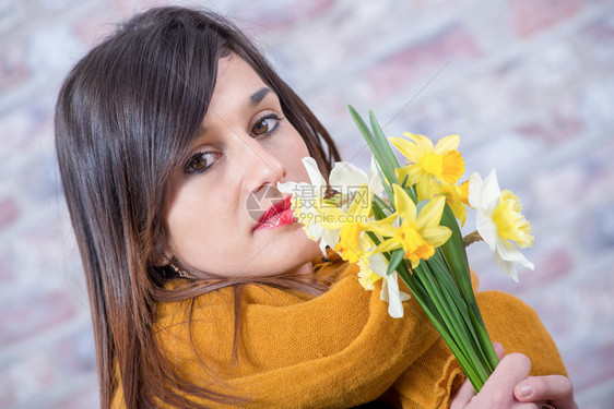 带着一束水仙花的黑发年轻女人图片