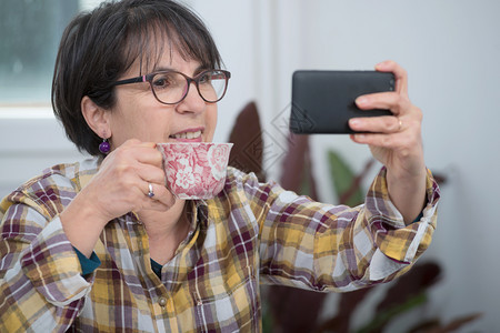 在家里使用智能手机的中年黑发妇女图片