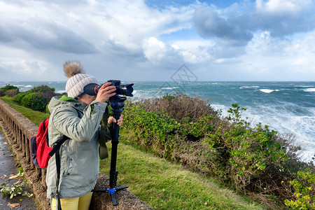 在法国比亚里兹暴风雨中工作的女摄影师图片