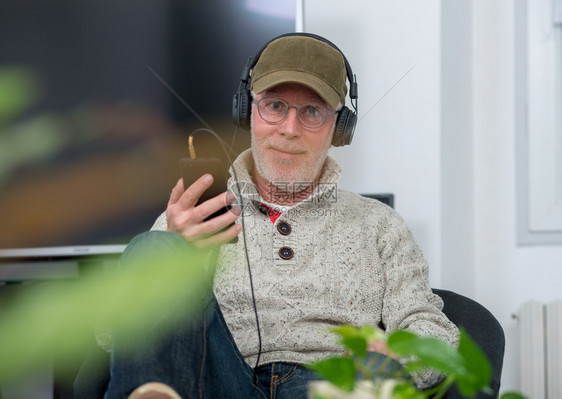 成年男子耳机盖帽在家听音乐图片