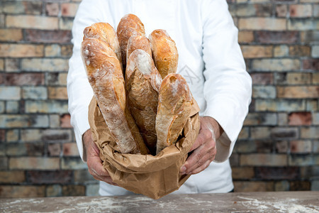a面包师持有传统法国面包背景图片