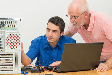 青年男子和老人修理计算机图片