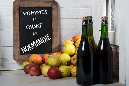 有机新鲜苹果和一瓶带有黑板的诺曼底苹果酒图片