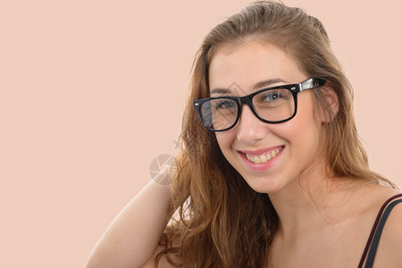 一个笑着的年轻女人带着黑色眼镜浅粉红背景图片