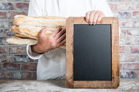 a面包师拿着法国和黑板图片