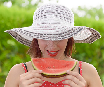 穿着夏帽子的漂亮女孩吃西瓜图片