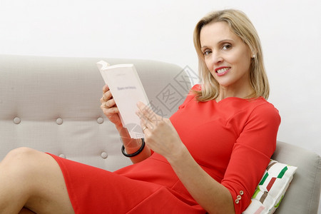 美丽的金发女在家沙上看书图片