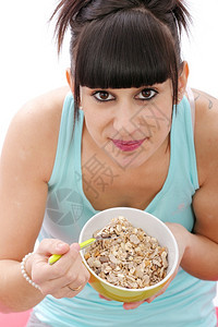 年轻的黑发女人吃一碗健康早餐麦片图片