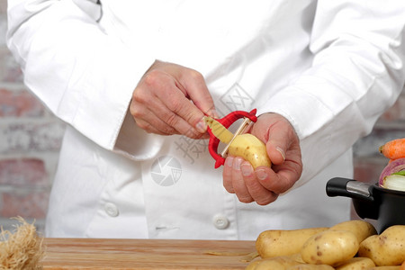 男人用红皮剥土豆的手图片