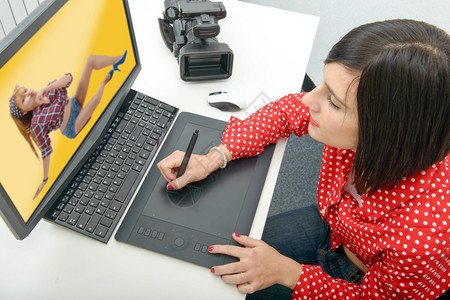 年轻黑发女设计师使用图形平板同时与计算机合作图片