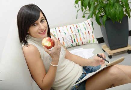 在家里吃苹果的年轻女学生背景图片