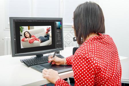 年轻黑发女设计师使用图形平板同时与计算机合作图片