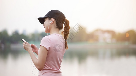 美丽的女人在公园里听音乐图片