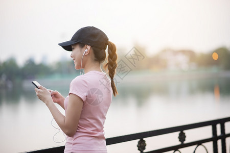 美丽的女人在公园里听音乐图片