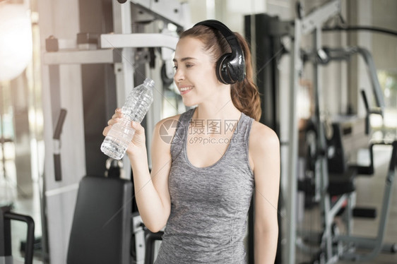 漂亮的年轻运动女子在健身房喝水康生活方式图片