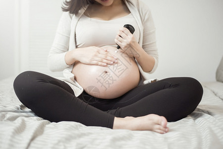 孕妇腹部涂抹乳霜的特写镜头图片