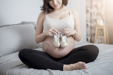 美丽的亚洲孕妇手拿小孩的鞋子图片