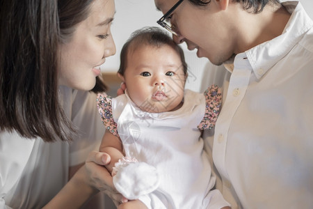 快乐的家庭爸妈和玩着他们可爱的新生婴儿图片