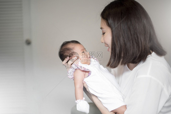 怀里抱着婴儿的年轻女子图片