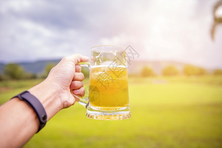 男人手在户外举着啤酒杯图片