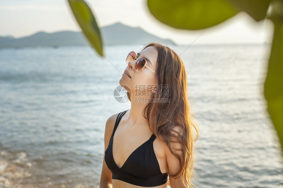 穿黑色比基尼的美女在沙滩上放松夏天的概念图片