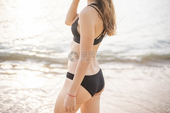 穿黑色比基尼的美女在沙滩上放松夏天的概念图片