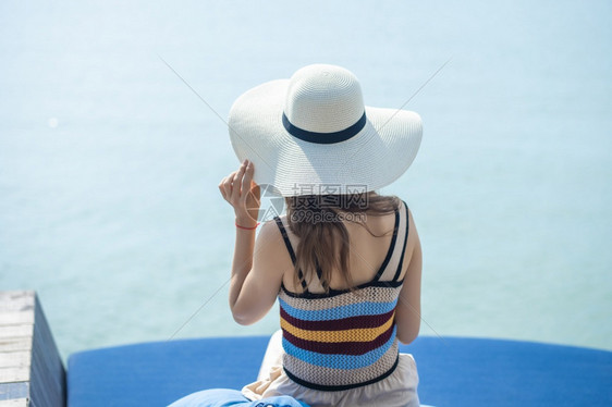 在海滩上戴白帽子的后背女人图片
