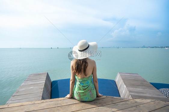 在海滩上戴白帽子的后背女人图片