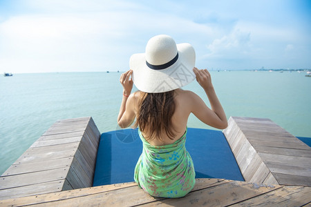 蚕蛹戴白在海滩上戴白帽子的后背女人背景