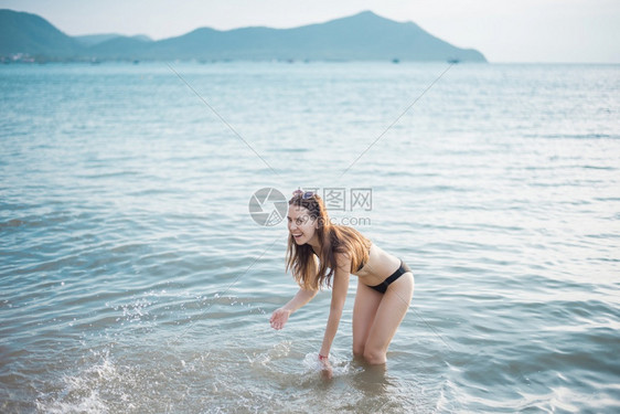 穿黑色比基尼的美女正在海滩上享受水图片