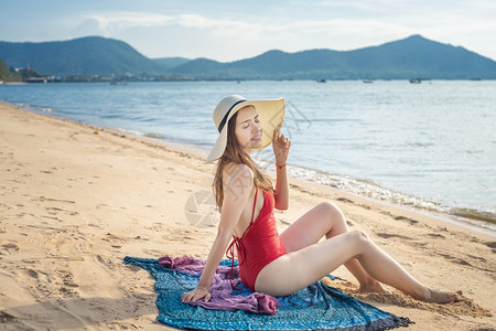 穿红泳衣的美女坐在沙滩上图片