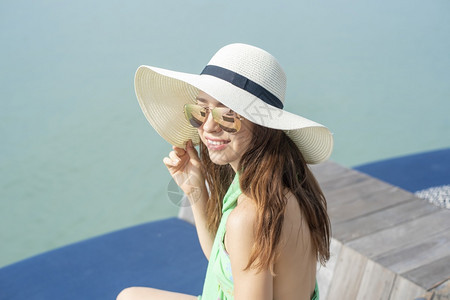 戴白帽子的漂亮女人坐在酒店和海滩上图片