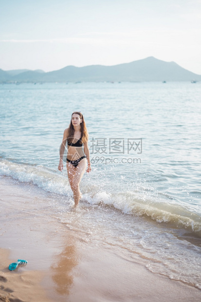 穿黑色比基尼的漂亮女人正在海上走夏天的概念图片