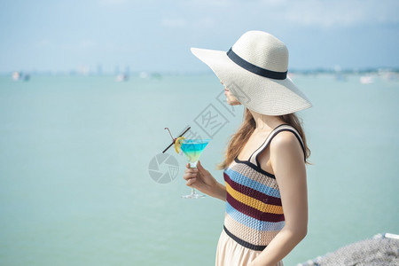 美丽的女人正在海滩喝冰水夏天在海滩喝水夏天的概念图片