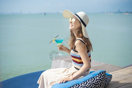 美丽的女人正在海滩喝冰水夏天在海滩喝水夏天的概念图片