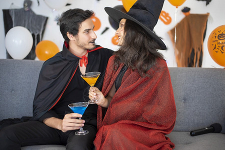 万圣节扮演女巫和吸血鬼干杯的情侣背景图片