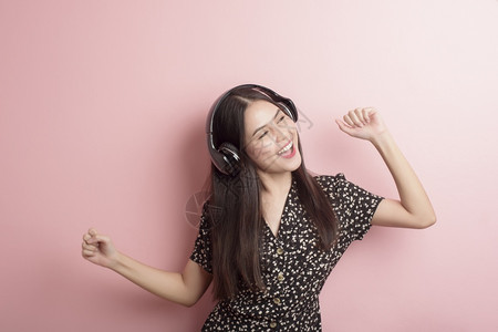 音乐情爱女人正享受着粉红色背景的耳机图片