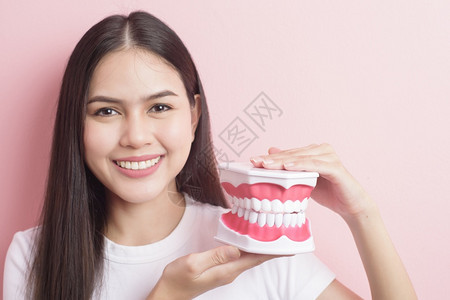 美丽的女人拿着牙齿假模型做科清洁示范图片